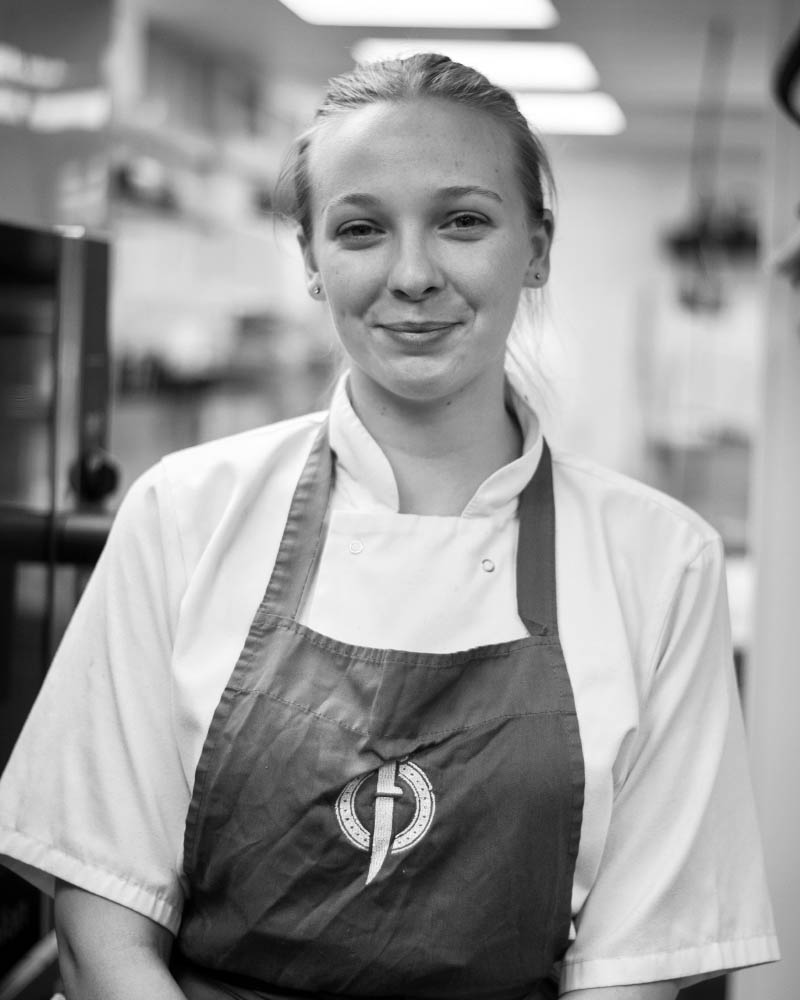 Meet Abigail, one of our skilled chefs at Fletcher's Restaurant, standing in the kitchen, dedicated to creating delicious dishes for our diners.